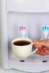Woman filling cup at water cooler