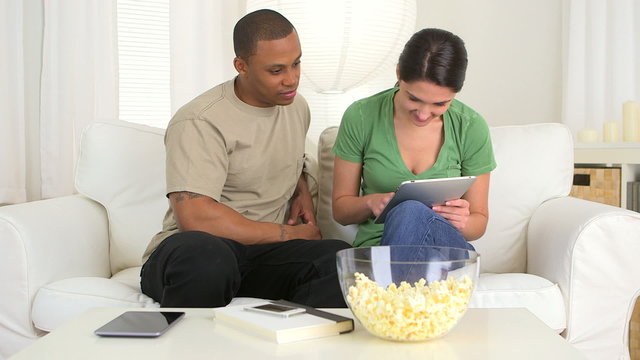 Happy African American and Caucasian couple using tablet pc on c