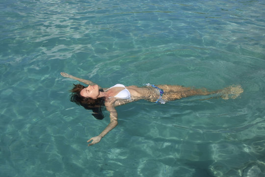 Young woman in bikini floating in clear water