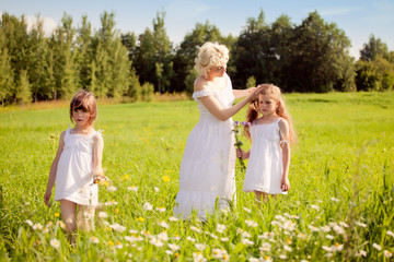 Naklejka na ściany i meble Mother and daughters relaxing on the meadow