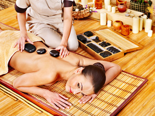 Woman getting stone therapy massage .