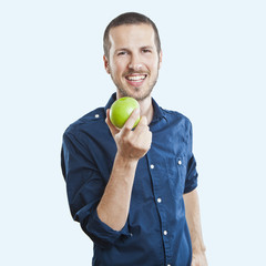 Cheerful beautiful man eating apple, isolated over white backgro