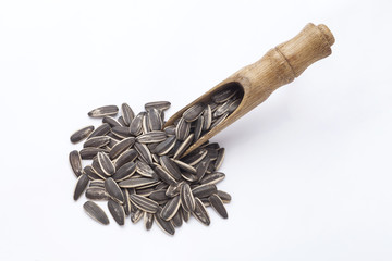 sunflower seeds in wooden scoop over white background