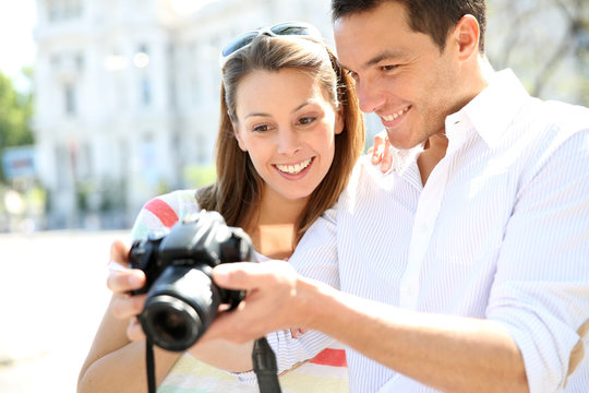 Happy couple looking at pictures on photo camera