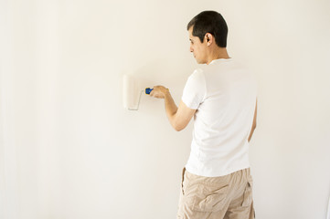 man painting white wall with roller