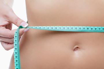 Female tummy with tape measure