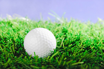 Golf ball on green field grass against blue sky
