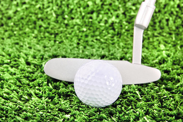 Golf ball and club on green grass