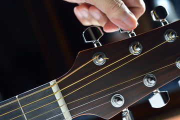 Obraz premium Hand tuning a guitar from headstock