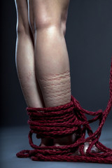 Slender woman's legs tied with red rope
