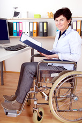 Disabled woman in wheelchair at desk