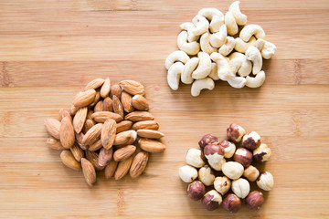 Three piles of nuts on a wooden board