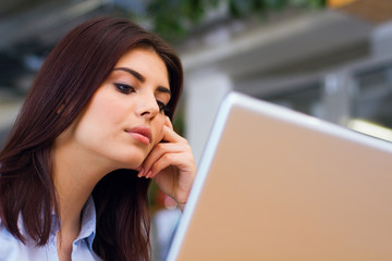 Portrait of a young pensive woman working with laptop