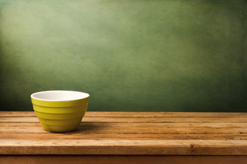 Empty green bowl on wooden table over grunge green background