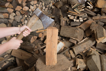 Holz hacken mit Axt auf Hackstock mit Scheiter im Hintergrund