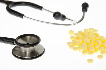 Stethoscope and medical pills tablets on white background.