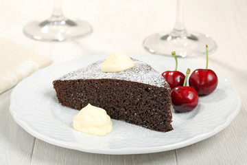 torta al cioccolato con crema e ciliege su piatto bianco