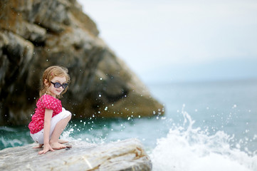 Adorable little girl sitting on a rock