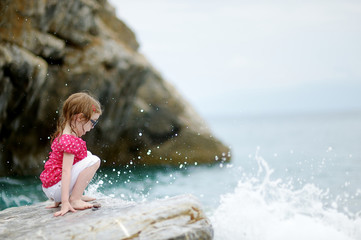 Adorable little girl sitting on a rock