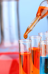 Laboratory pipette with drop of color liquid over glass test