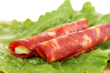 Salami rolls on wooden board, close up