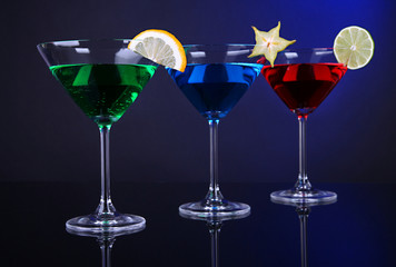Alcoholic cocktails in martini glasses on dark blue background