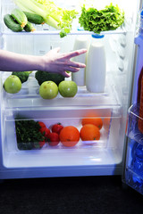 Woman's hand reaching out for food from the refrigerator, close