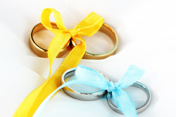 Wedding rings tied with ribbon on cloth background