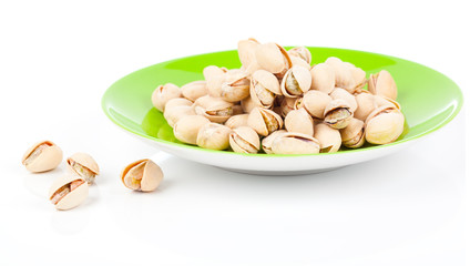 pistachios in a green plate, isolated on white background