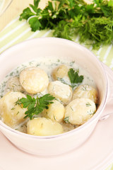 Tender young potatoes with sour cream and herbs in pan