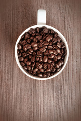 Coffee beans and coffee cup on a wooden floor.