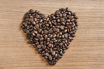 Heart shaped coffee beans with a wooden surface.