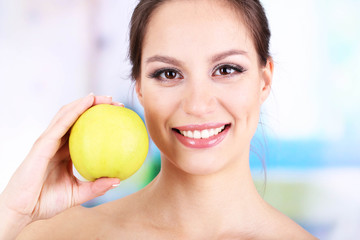 Smiling woman with apple on bright background