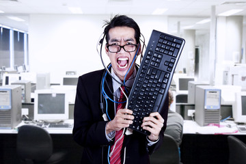Crazy businessman hold keyboard at office