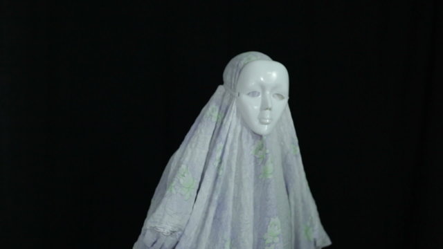 A man in scary mask and sheet, over dark background