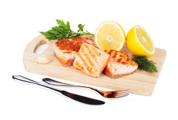 Grilled salmon with lemon and herbs on cutting board