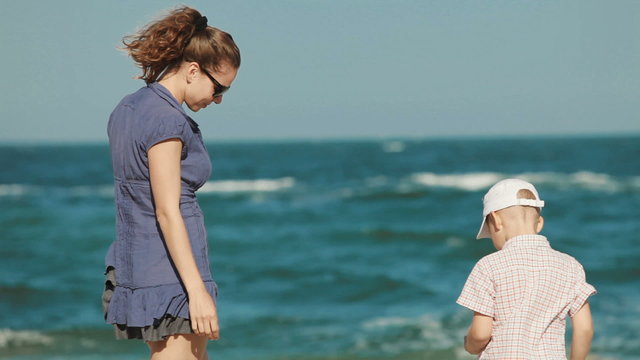 young mother with her son play in the sand at the beach