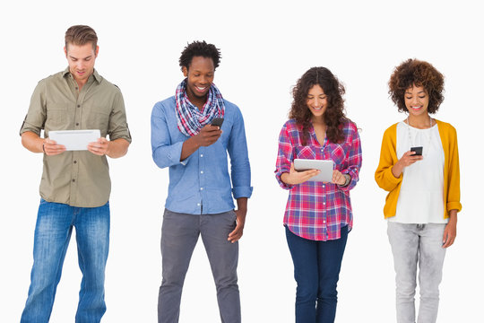 Fashionable friends standing in a row using media devices