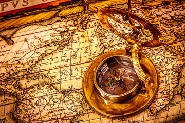 Vintage compass lies on an ancient world map.