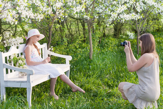 Mother photographing her daughter at spring garden
