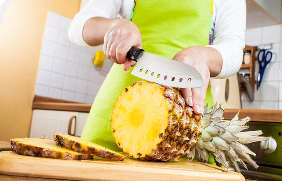 Woman's hands cutting pineapple