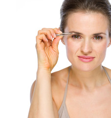 Beauty portrait of young woman using tweezers