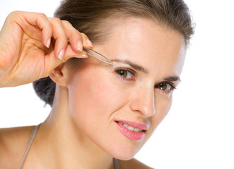 Fototapeta premium Beauty portrait of young woman using tweezers