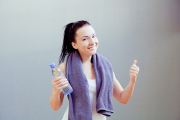 Young woman at the gym drinks water 