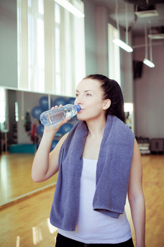 Young woman at the gym drinks water 