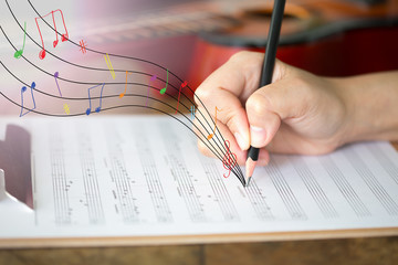 Hand with pencil and music sheet