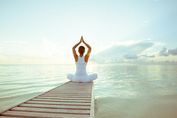 Blanke vrouw die yoga beoefent aan de kust