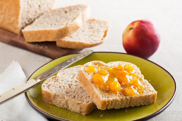 Spelt bread slices on a dish with peach marmalade