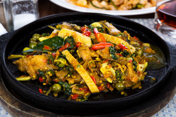 Fried fish with fresh herbs and  spicy sauce served on iron hot