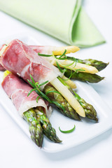 Green and white asparagus wrapped in prosciutto ham - obrazy, fototapety, plakaty
